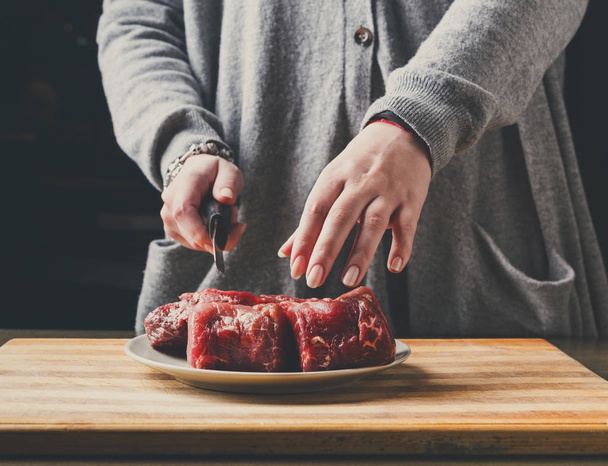 Preparing filet mignon. Female hands cutting meat for cooking - Foto, imagen