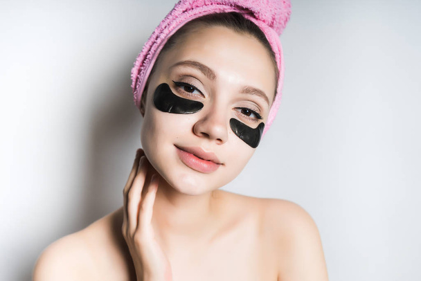 A woman enjoys skin and hair care, a black mask under the eyes - Foto, imagen