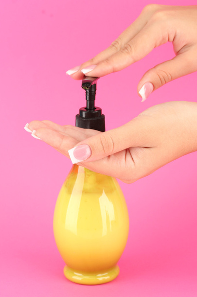woman squeezing lotion on her hand, on pink background close-up - Foto, immagini