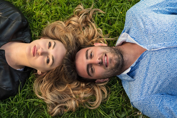 Top view of two friends smiling while looking towards the sky as they laying at the grass. - 写真・画像