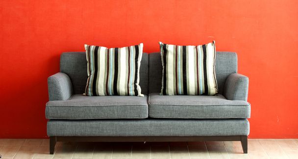 sofá gris puesto sobre fondo de estuco rojo
 - Foto, imagen