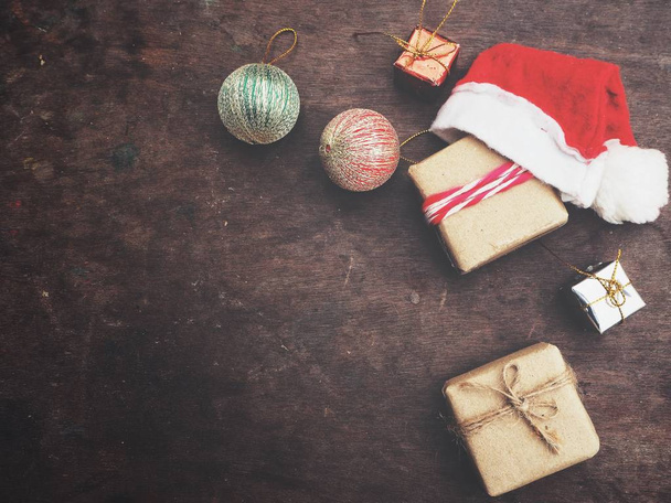 茶色の木製の背景にプレゼントとクリスマス帽子 - 写真・画像