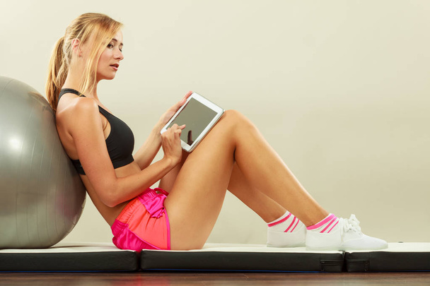 Fit woman sitting on floor with tablet pc - Photo, Image