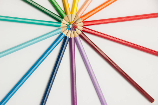 A group of pencils folded in rainbow colors in a circle on a whi - Photo, Image