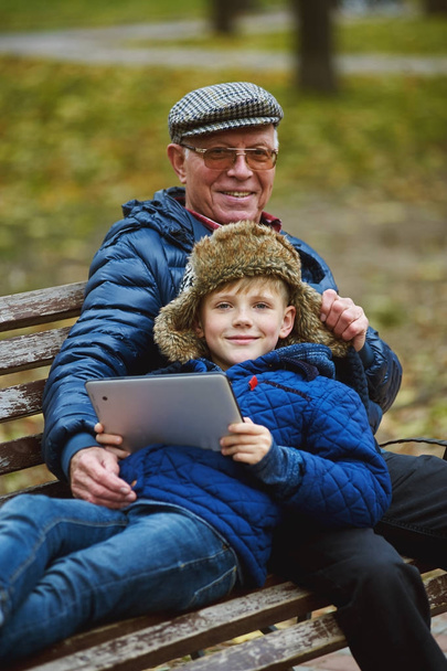 Enkel mit Großvater auf Spaziergang im Herbstpark  - Foto, Bild