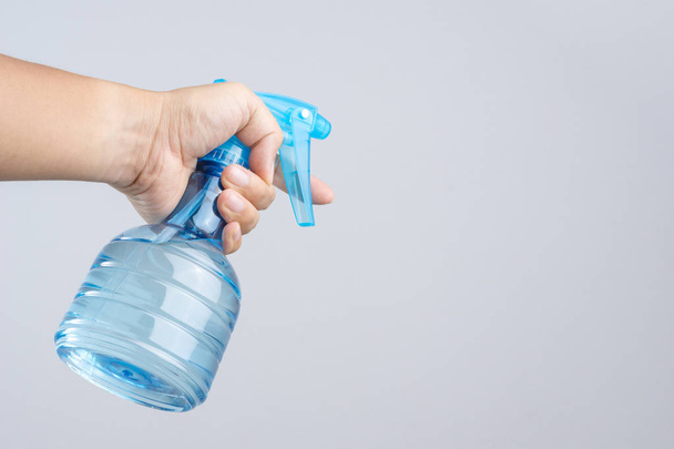 Hand holding blue plastic spray bottle contain pure water on white background - Φωτογραφία, εικόνα