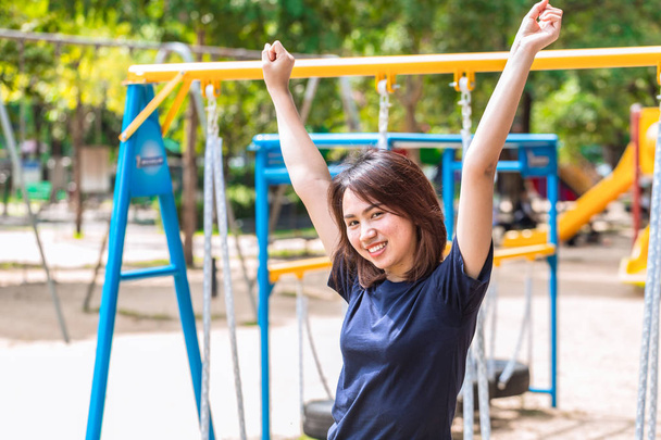 adolescente levantar-se duas mãos para mostrar suas mulheres saudáveis fortes e sorrir no parque
 - Foto, Imagem