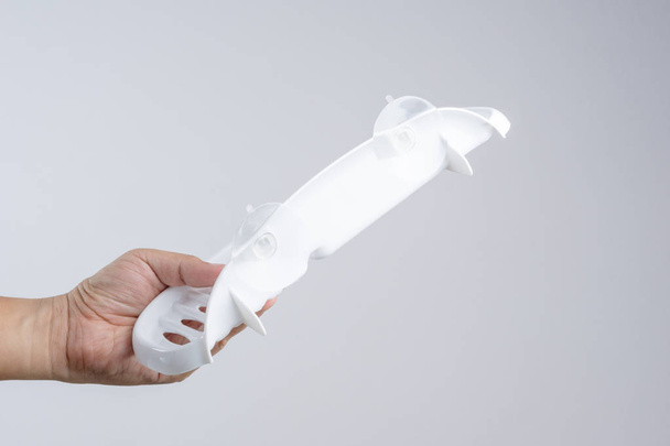 Ręka trzyma plastikową półkę z przeźroczystą przyssawkę do korzystania w WC i kuchnia na białym tle - Zdjęcie, obraz