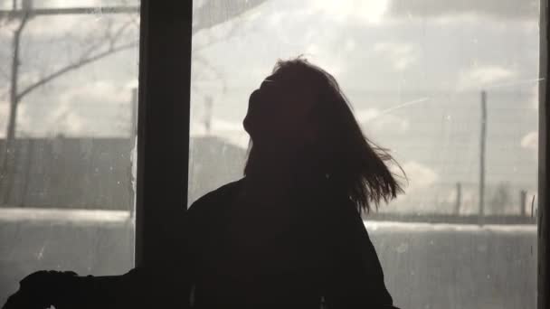 Silhouette of a happy girl dancing in front of a window - Záběry, video