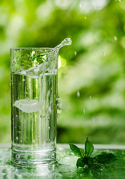 Cool fresh water with ice and mint. Splash in glass. Healthy life concept - Photo, Image