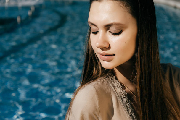 linda y hermosa chica sentada junto a la piscina y mirando hacia otro lado
 - Foto, imagen