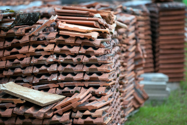 vieilles tuiles de toit en tuiles d'argile empilées sur des palettes en bois. Le contexte de la restauration de la construction et de la logistique
 - Photo, image