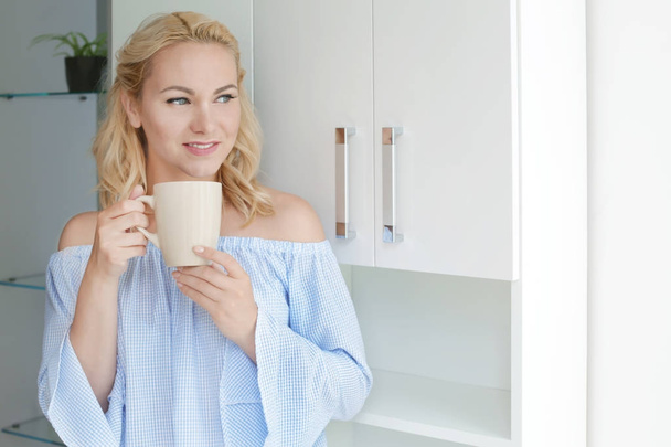 Beautiful woman drinking coffee in kitchen at home - Foto, afbeelding