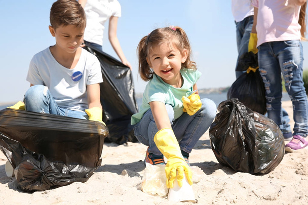 Young volunteers and children collecting garbage on beach - Fotografie, Obrázek