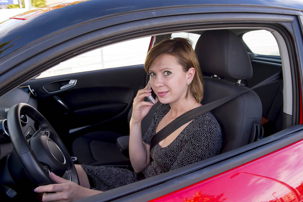 nainen puhuu onnellinen matkapuhelimessa pitäen auton ohjauspyörän ajo hajamielinen
 - Valokuva, kuva