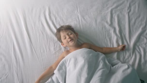 Little boy stretching in bed after wake up - Filmagem, Vídeo