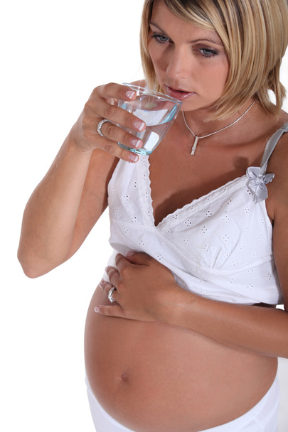 Pregnant woman drinking a glass of water - Photo, Image