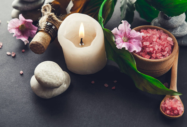 Essenciais de spa, incluindo vela, sal, pedras, óleo e folhas verdes
 - Foto, Imagem