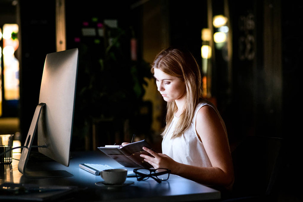 Businesswoman in her office at night working late. - Foto, afbeelding