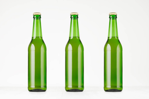 Three green longneck beer bottles 500ml, mock up. Template for advertising, design, branding identity on white wood table. - Foto, immagini