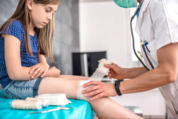 doctor bandaging girl knee - Zdjęcie, obraz