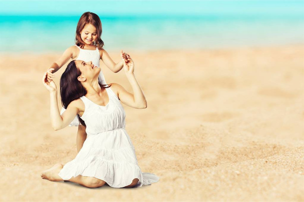 Äiti ja tytär halaavat hiekkarannalla
 - Valokuva, kuva