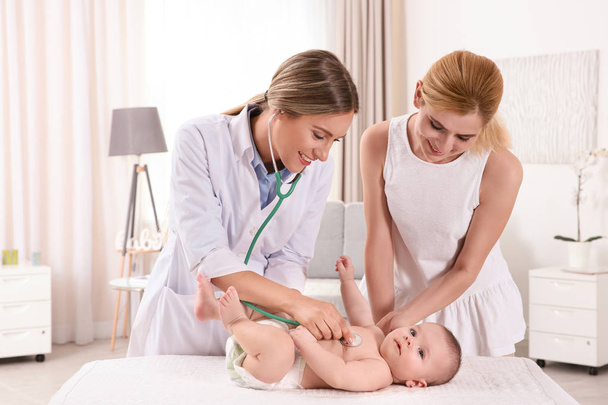 Doctor examining baby with stethoscope at home - Valokuva, kuva
