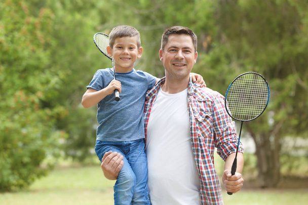 Happy father and son with tennis rackets in park - Foto, Imagem