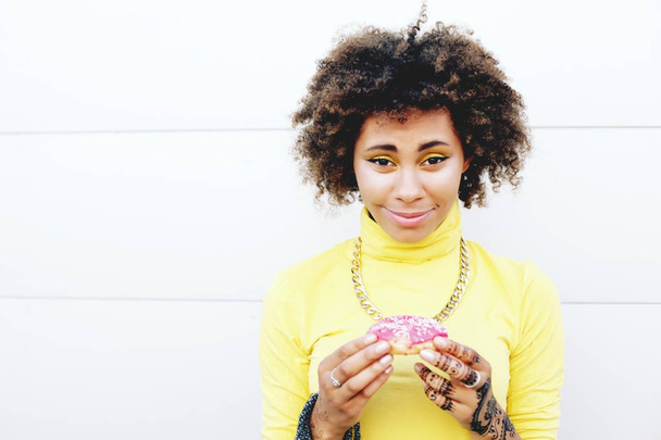 woman in yellow sweater holding donut  - Zdjęcie, obraz