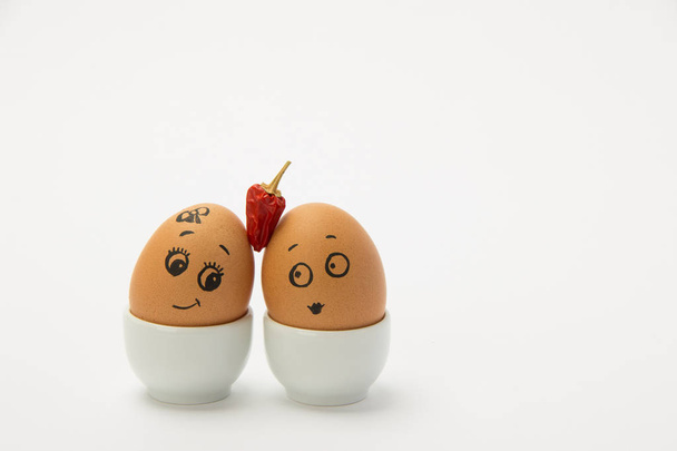 Dos huevos de pollo con caras de amor y pimiento rojo sobre blanco
  - Foto, Imagen