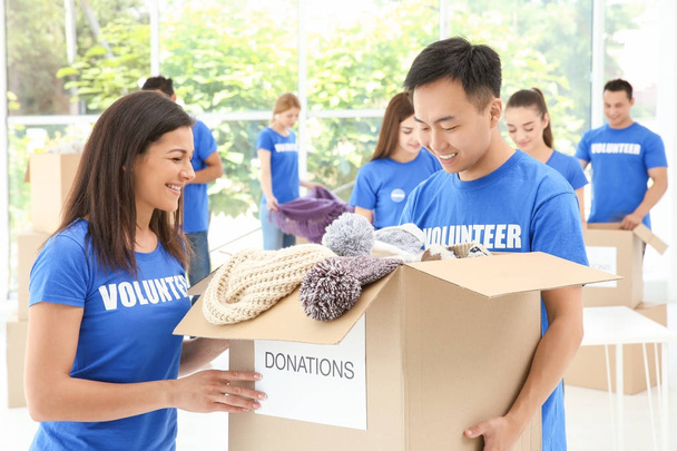 Two happy teen volunteers holding box with donations indoors - Foto, imagen