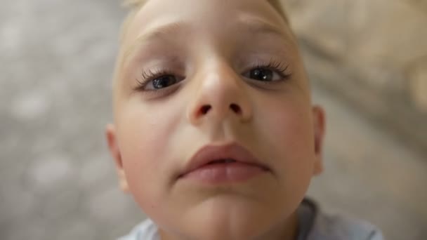 A little boy with beautiful dark eyes and large eyelids kisses the cameras objective. Beautiful little boy - Filmagem, Vídeo