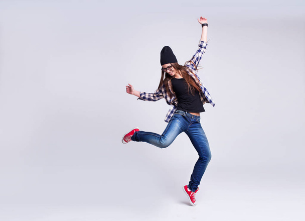 Dancing hipster girl in glasses and black beanie - Фото, изображение