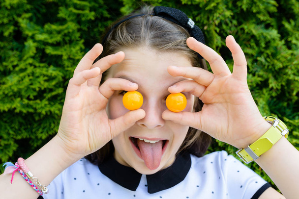 Portrait de jeune fille souriante et heureuse tenant, montrant de petites tomates sur ses yeux
 - Photo, image