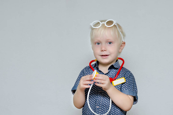 Pieni poika leikkii lääkäriä. Lelulasit ja fonendoskooppi. Muotokuva
 - Valokuva, kuva