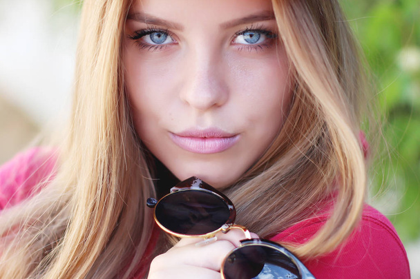 attractive young woman holding sunglasses - Фото, зображення