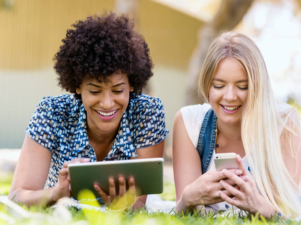 Two young women with tablet in park - Foto, Imagen
