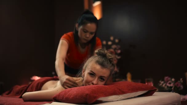 asian female in red uniform doing traditional thai massage in spa salon - Materiał filmowy, wideo