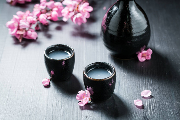 Prepared to drink sake with flowers of blooming cherry - Foto, afbeelding