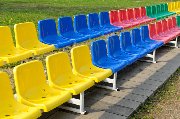 Vícebarevné lavičky pro sportovní fanoušky stojí ve dvou řadách. - Fotografie, Obrázek