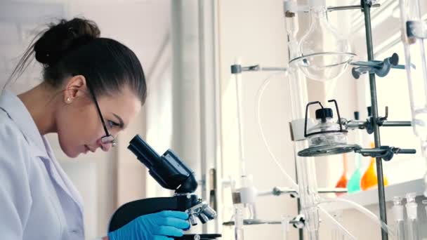 junge brünette Frau in weißer Uniform arbeitet in modernem Labor  - Filmmaterial, Video