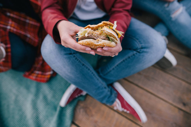 Tasty burger in womans hands. Takeaway junk food - Fotoğraf, Görsel