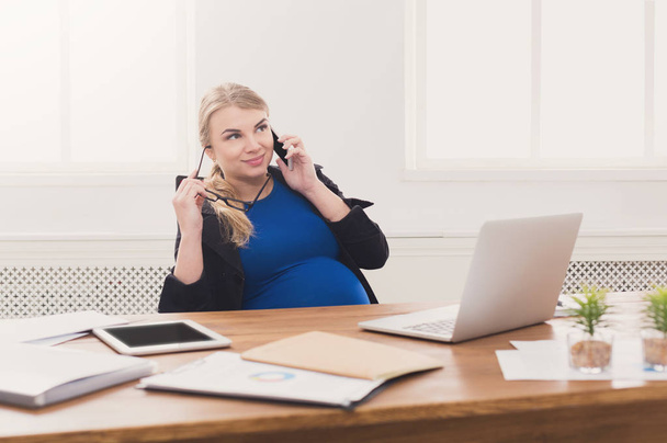 Donna d'affari incinta al lavoro che parla al telefono
 - Foto, immagini