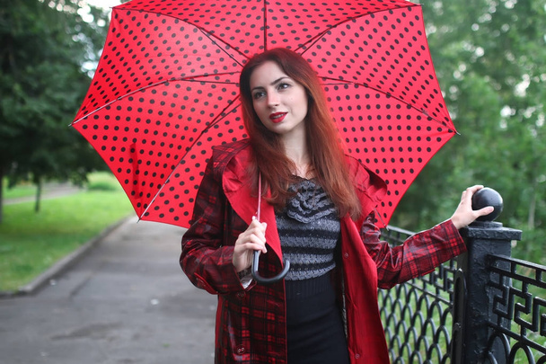 vrouw in een regenjas en een paraplu - Foto, afbeelding