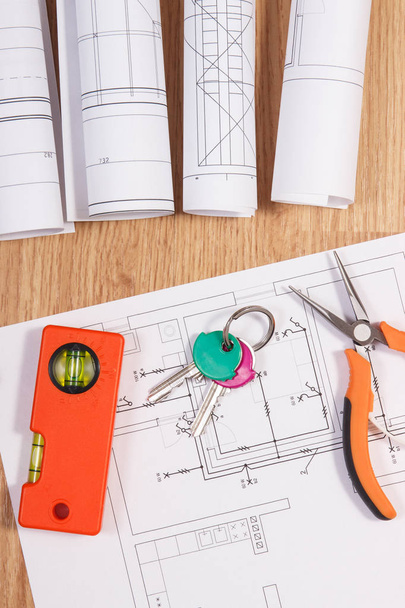 Chaves de casa com desenhos elétricos ou plantas e ferramentas de trabalho laranja, conceito de casa de construção
 - Foto, Imagem