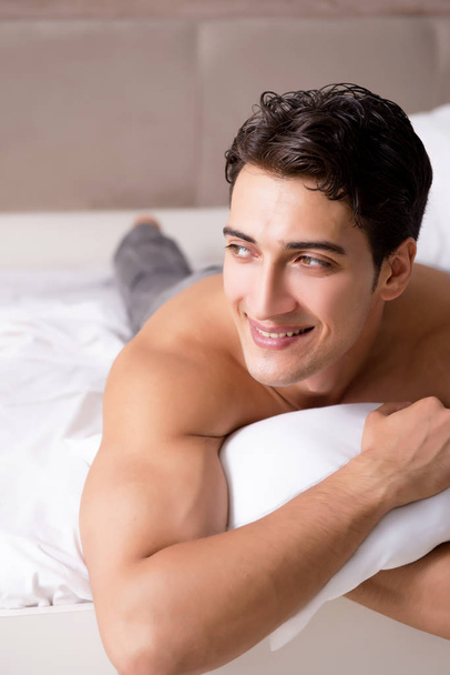 Young handsome shirtless guy showing nude torso sexy on bed at h - Zdjęcie, obraz