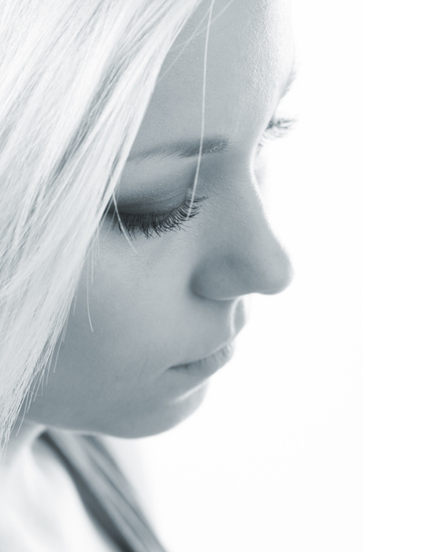 Profile of the beautiful sad girl with long blond hair isolated on white in blue tones - 写真・画像
