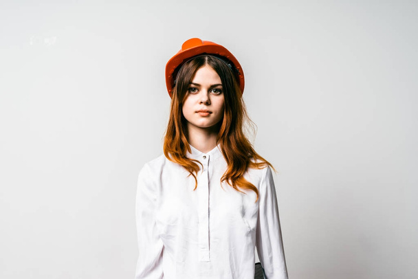beautiful girl in an orange hat and white shirt looks at the camera - Zdjęcie, obraz