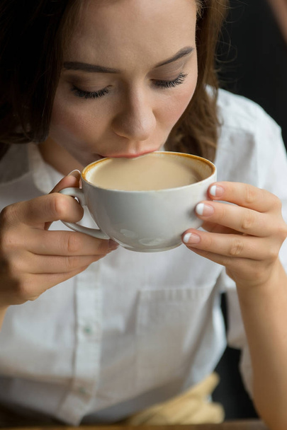 Close up of young beautiful woman drinking coffee in a cafe - Photo, Image