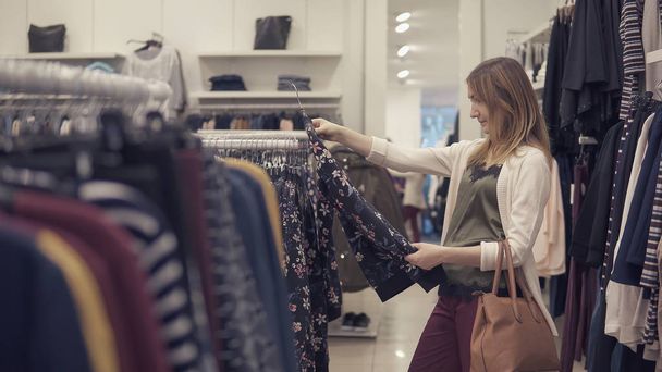 Красивая женщина ищет одежду в магазине одежды
 - Фото, изображение